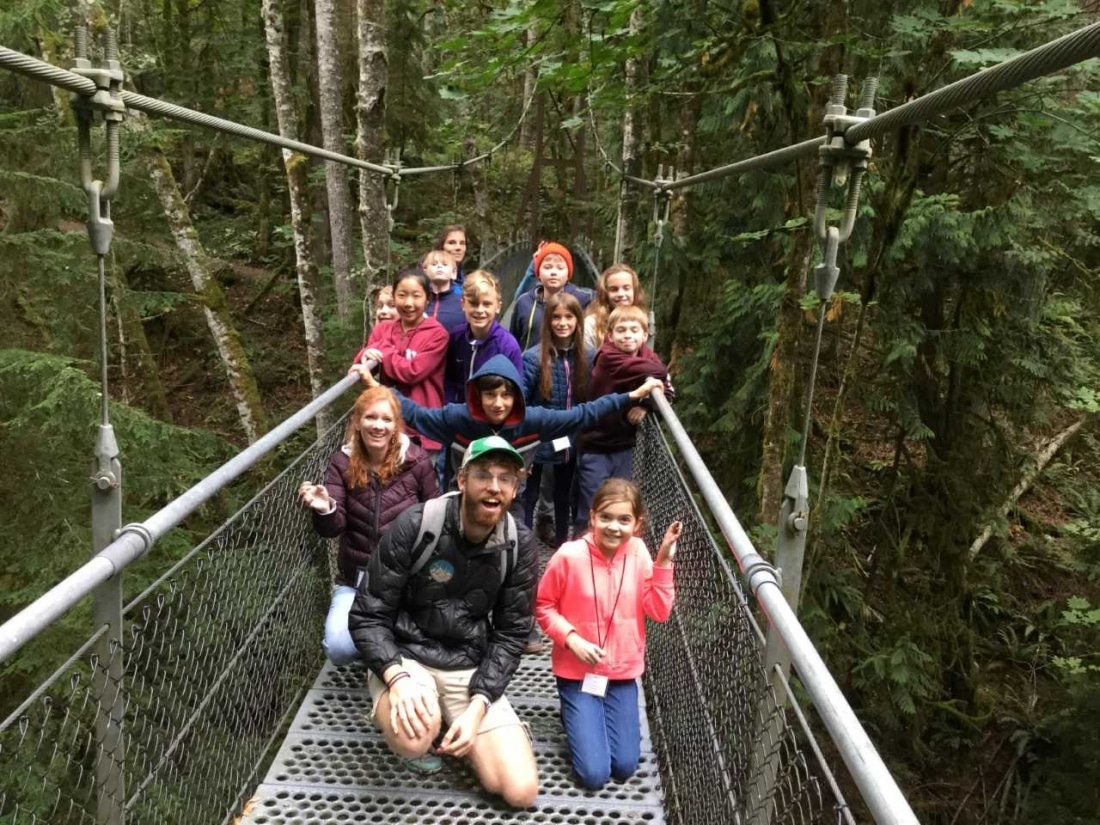 Criqui poses on the suspension bridge with a group of smiling School Overnight Program students.