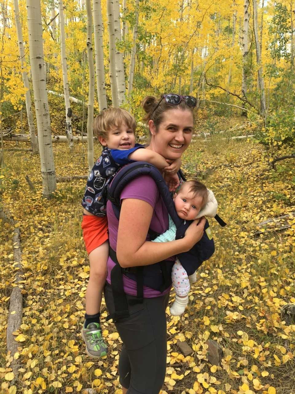 Lauren Watel carrying her two children while hiking in the forest.