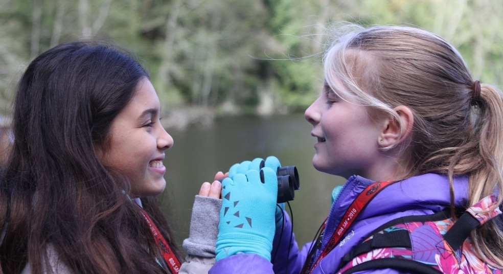 Two School Overnight Program students share binoculars on Mac's Pond.