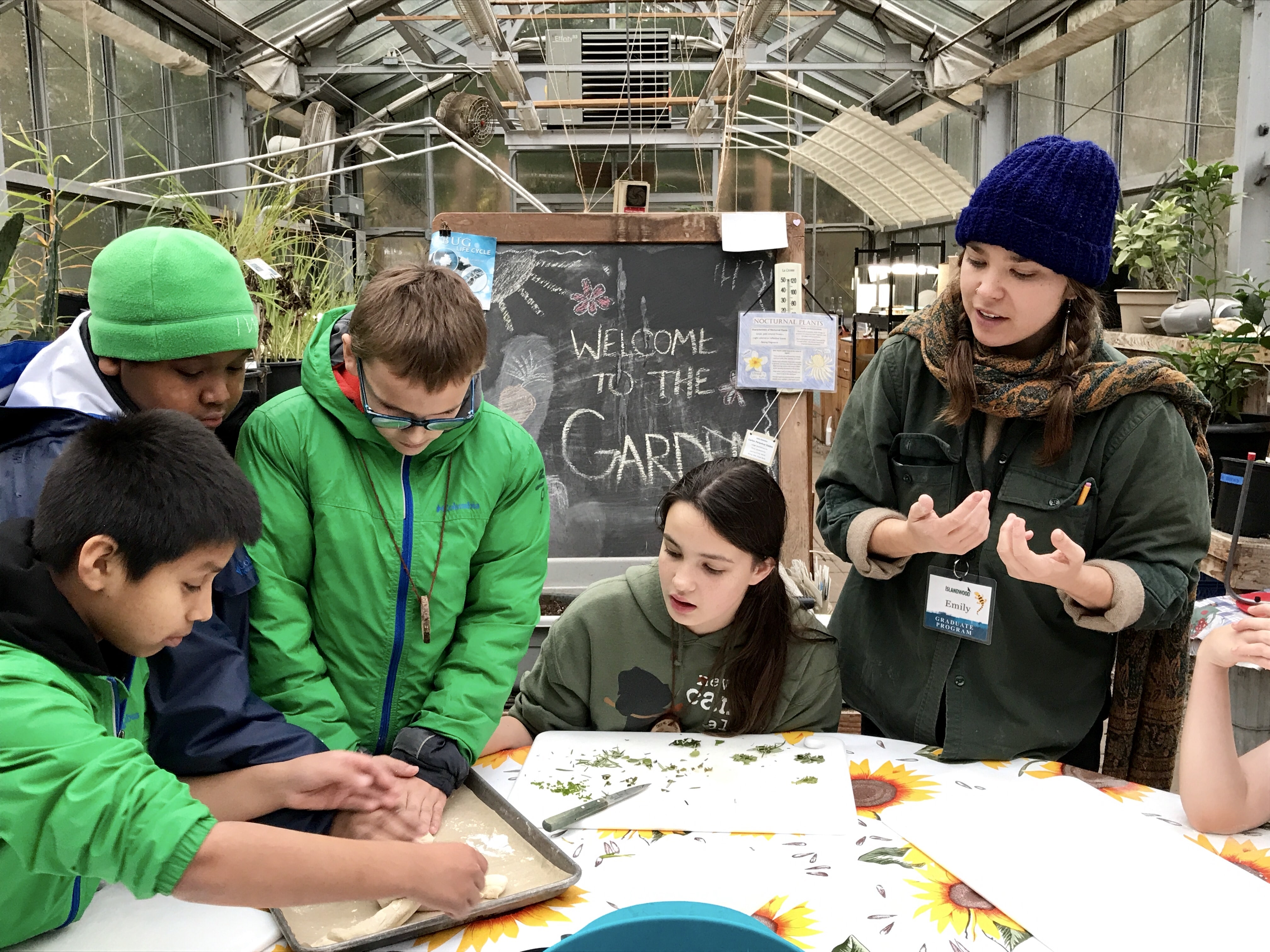 A student enrolled in IslandWood's Graduate Program in Environmental Education & Equity with their students in the greenhouse