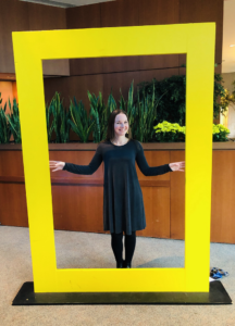 2018 Patsy Collins Award recipient Jennie Warmouth stands inside a National Geographic-style yellow frame. She is preparing to conduct research in the arctic beginning next week.