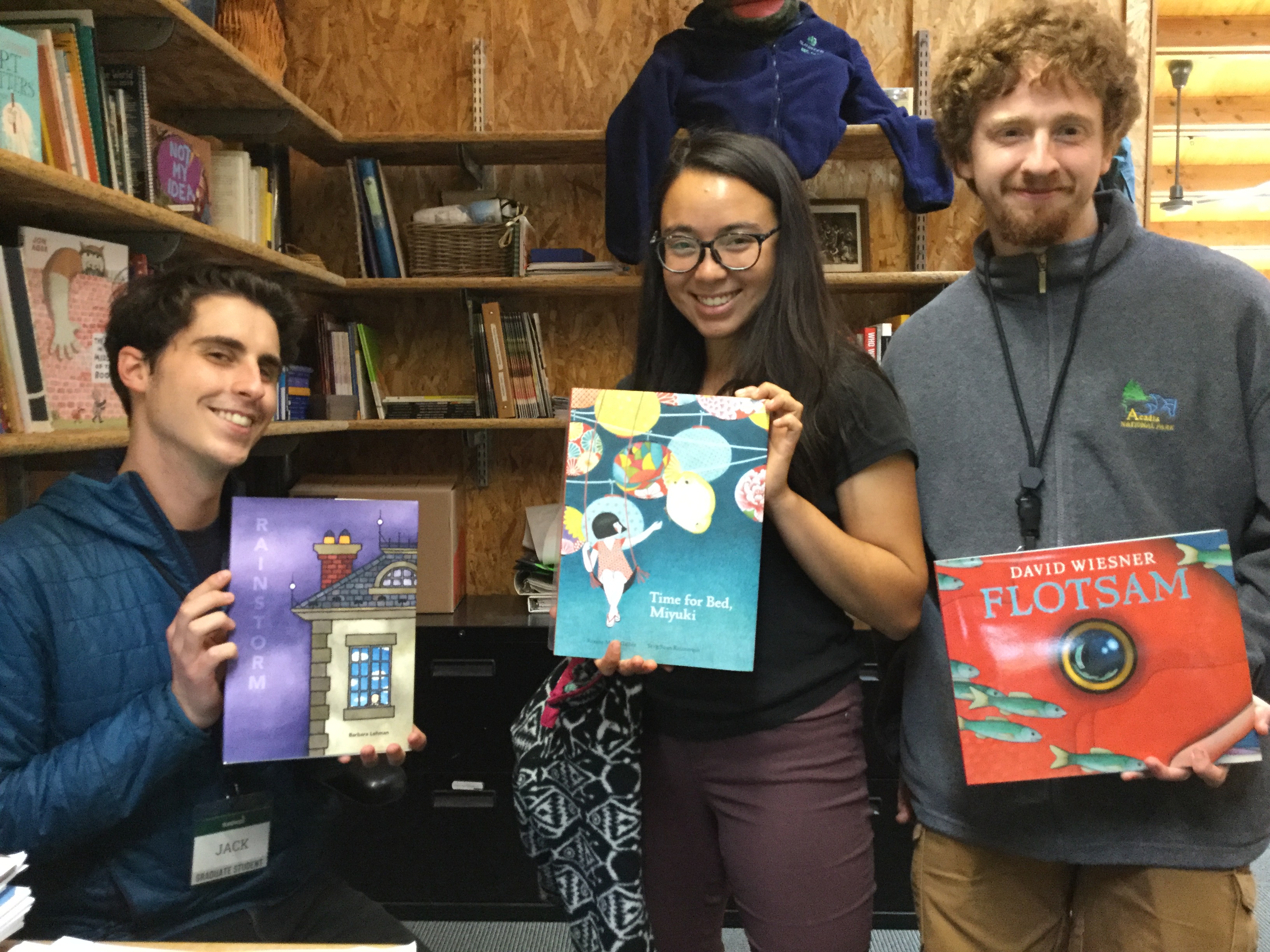 IslandWood graduate students hold up children's books from the collection in Déana's office.